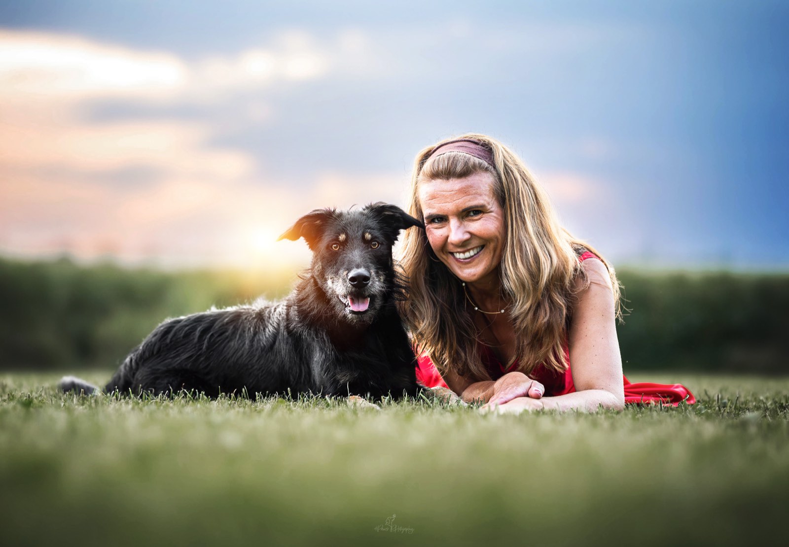 Verena Berg liegt lächelnd im Gras neben ihrem Hund